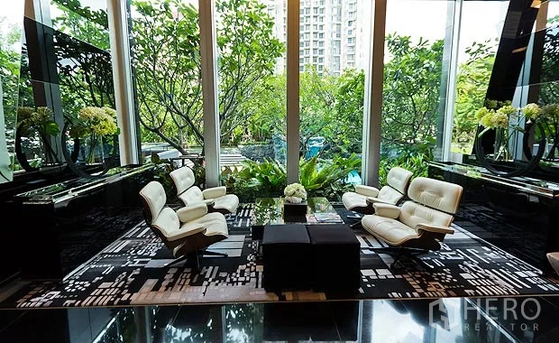 Condominium for rent in Ratchathewi, Bangkok - Elegant lobby lounge with Eames-style chairs and garden views through tall windows