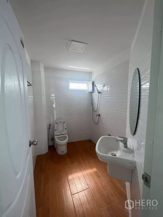 带办公室的家 出租在Prawet, Bangkok - 浴室白色墙砖与木纹地板，配淋浴和洗手盆。