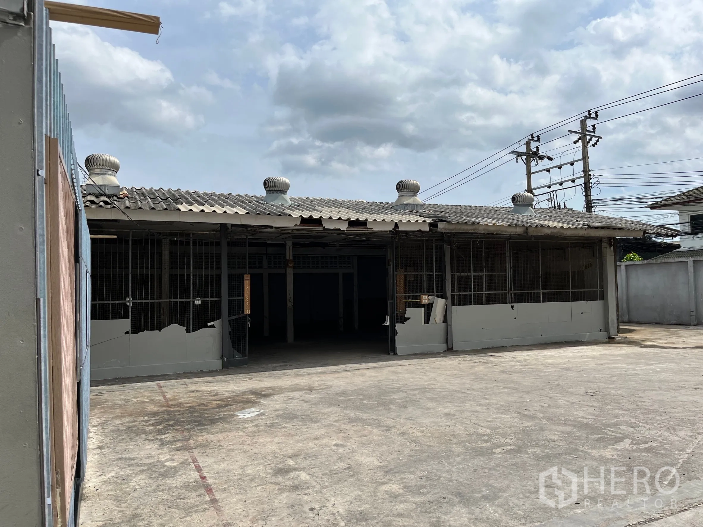 คลังสินค้า ให้เช่าในBangkok - ด้านหน้าโกดังพร้อมประตูบานเลื่อน พัดลมหลังคา และลานหน้าอาคาร