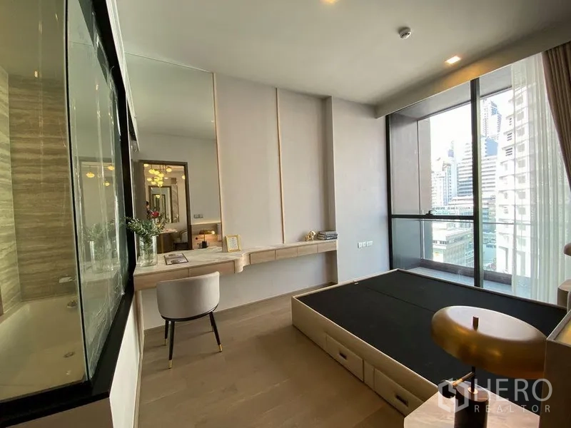 คอนโด ให้เช่าในWatthana, Bangkok - ห้องนอนมีโต๊ะทำงาน บานหน้าต่างสูงจรดเพดานเปิดสู่ระเบียงและวิวสกายไลน์ พร้อมผนังกระจกกั้นห้องน้ำ