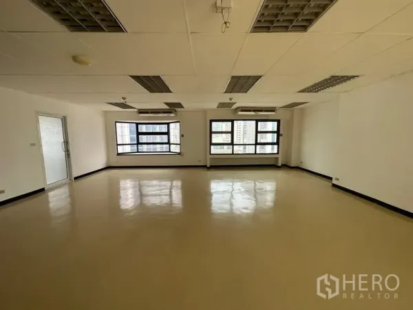 办公空间 出租在Pathum Wan, Bangkok - 开放式办公区，宽大窗户、城市景观，壁挂空调与网格灯。