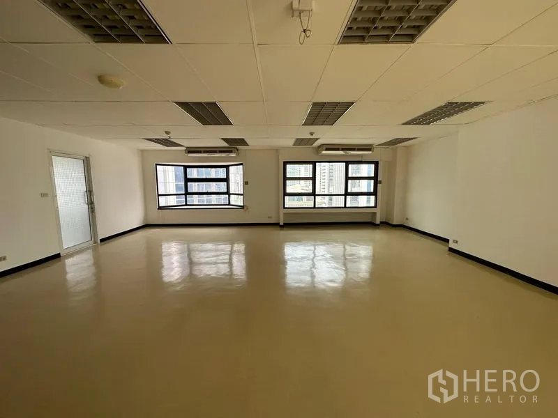 办公空间 出租在Pathum Wan, Bangkok - 开放式办公区，宽大窗户、城市景观，壁挂空调与网格灯。