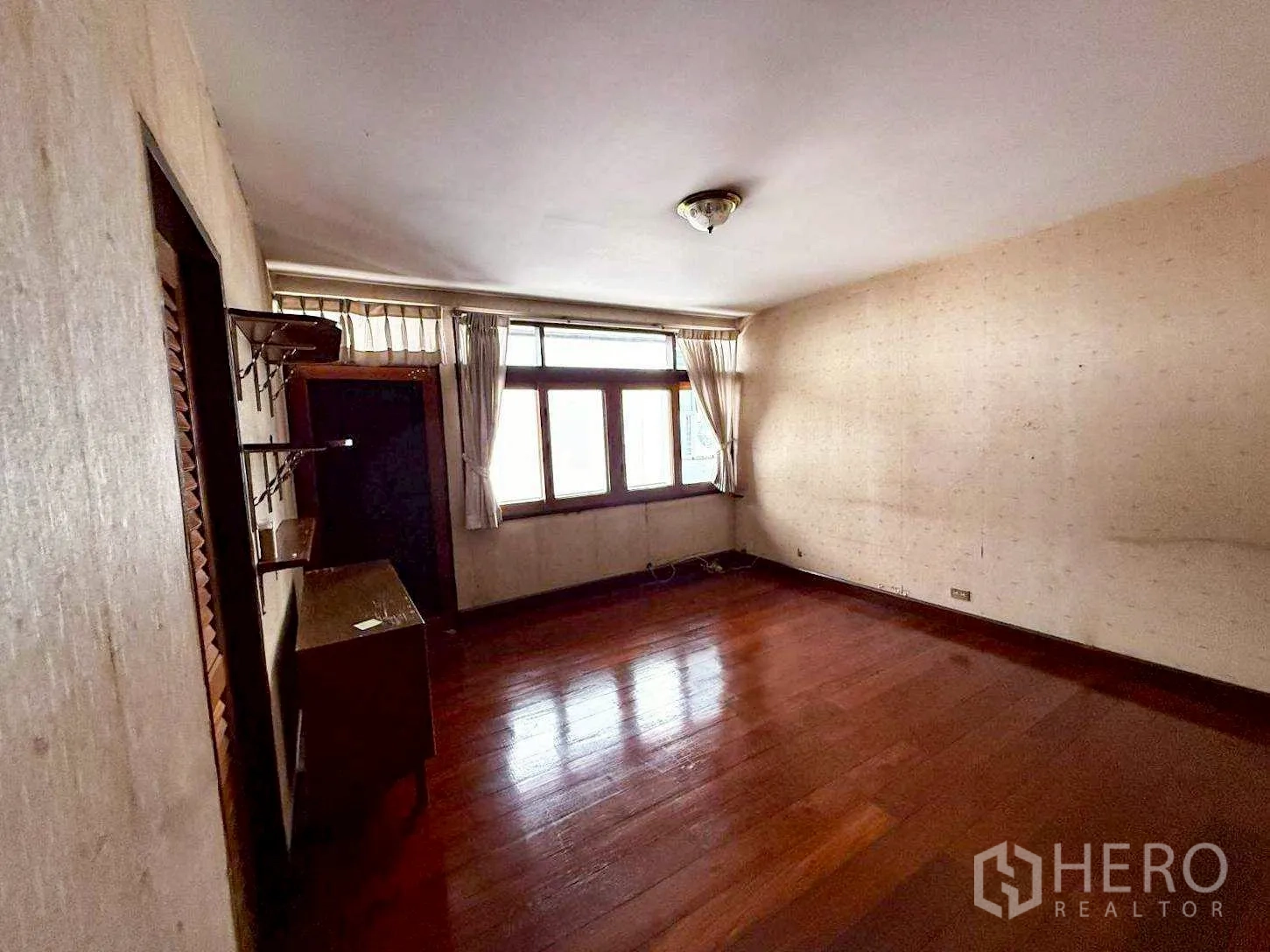 Home Office for rent in Bang Rak, Bangkok - Spacious room with window, minimal furniture and polished wood floor.