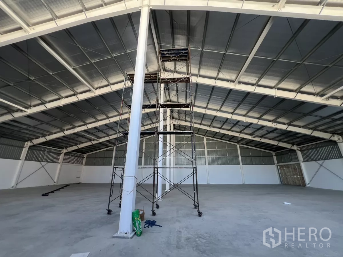 Warehouse for rent in Min Buri, Bangkok - Wide clear-span storage space with scaffolding under an insulated metal roof.