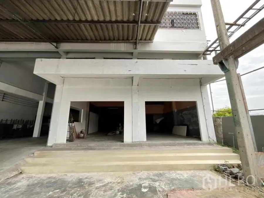 Warehouse for rent in Bang Phli, Samut Prakan - Front view of a white warehouse with dual bay entrances, covered canopy and concrete steps.