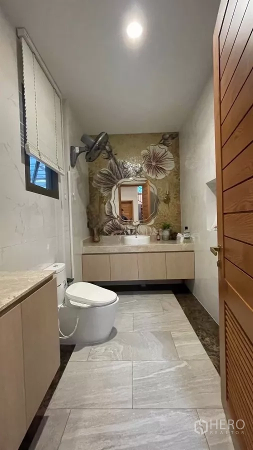 Detached House for rent in Prawet, Bangkok - Bathroom with floral accent wall, floating vanity and tiled floor.