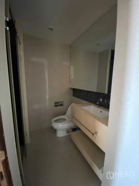 Condominium for sale in Ratchathewi, Bangkok - Second bathroom with large mirror, floating vanity and toilet in neutral tones.