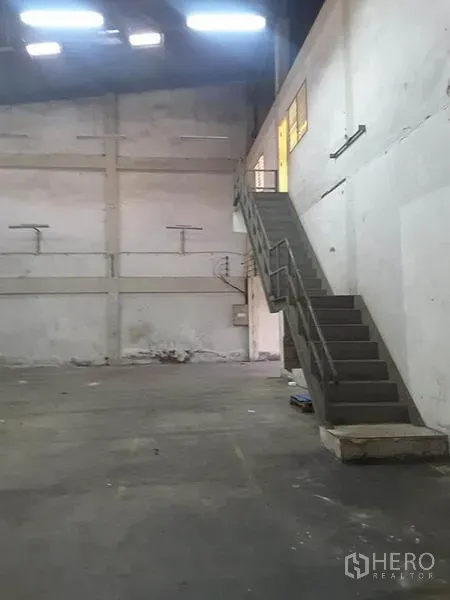 Factory for rent in Mueang Ratchaburi, Ratchaburi - Open warehouse space with high walls and a steel staircase leading to mezzanine offices.