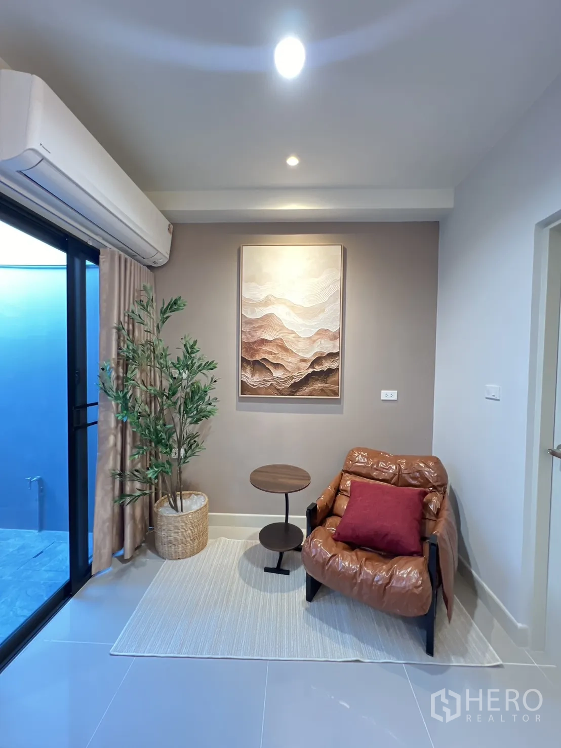Townhouse for rent in Bang Phli, Samut Prakan - Reading nook with an accent chair, side table and potted plant beside a sliding door.