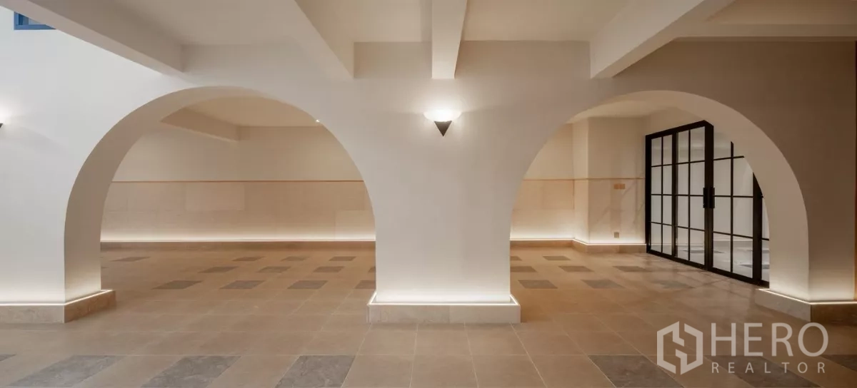 带办公室的家 出售在Phra Khanong, Bangkok - 宽敞多功能大厅，白色拱券、地砖与黑框玻璃门。