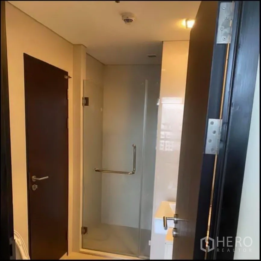 Condominium for rent in Watthana, Bangkok - Modern bathroom with glass-enclosed shower and warm lighting.