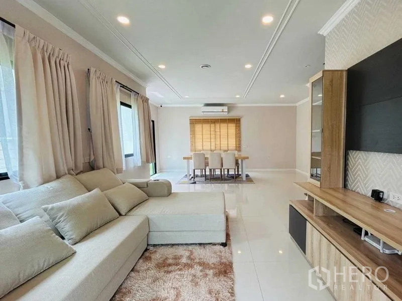 Detached House for rent in Khlong Sam Wa, Bangkok - Long living-dining space with built-in TV unit and corner sofa