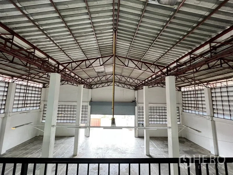Warehouse for rent in Min Buri, Bangkok - Central view of steel roof trusses and loading door inside the warehouse.
