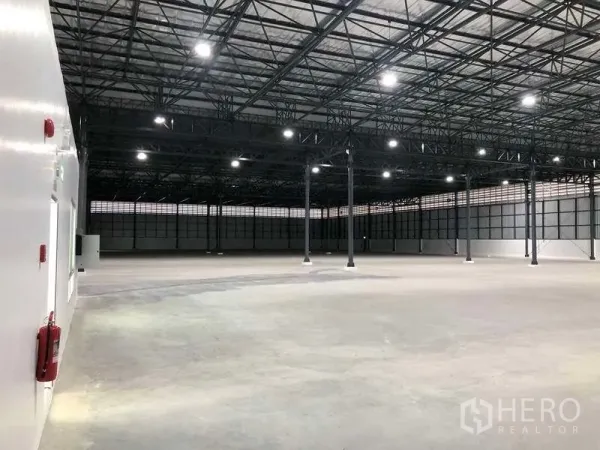 Factory for rent in Bang Sao Thong, Samut Prakan - Vast clear-span warehouse floor with steel truss roof and LED lighting.