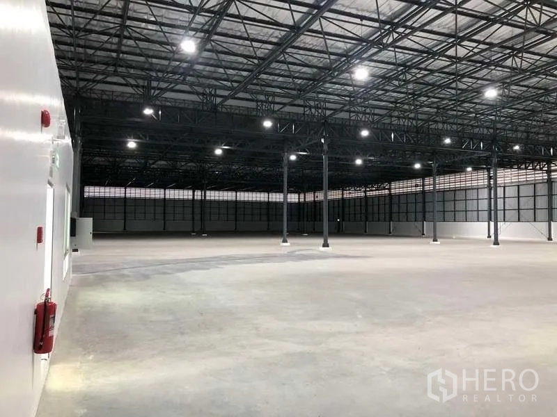 Factory for rent in Bang Sao Thong, Samut Prakan - Vast clear-span warehouse floor with steel truss roof and LED lighting.