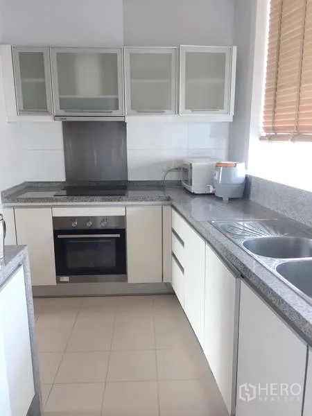คอนโด ขายในKhlong Toei, Bangkok - ครัวรูปตัวแอล เคาน์เตอร์หินแกรนิต เตาไฟฟ้า เตาอบ และอ่างล้างจานคู่ติดหน้าต่าง