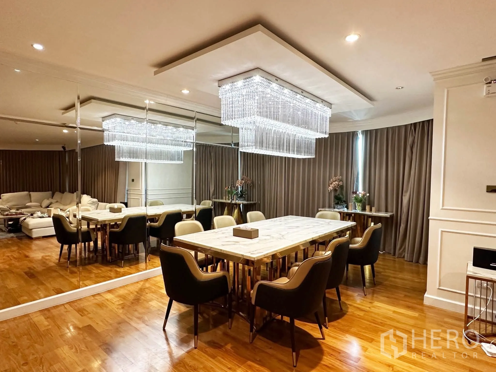 Condominium for sale in Khlong San, Bangkok - Formal dining room with mirrored wall, marble-top table, and chandelier lighting.