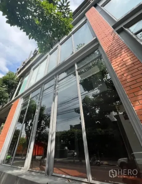 零售空间 出租在Khlong Toei, Bangkok - 曼谷现代商铺外立面，超高玻璃与红砖装饰。