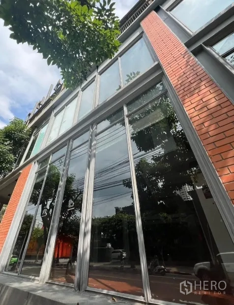 零售空间 出租在Khlong Toei, Bangkok - 曼谷现代商铺外立面，超高玻璃与红砖装饰。