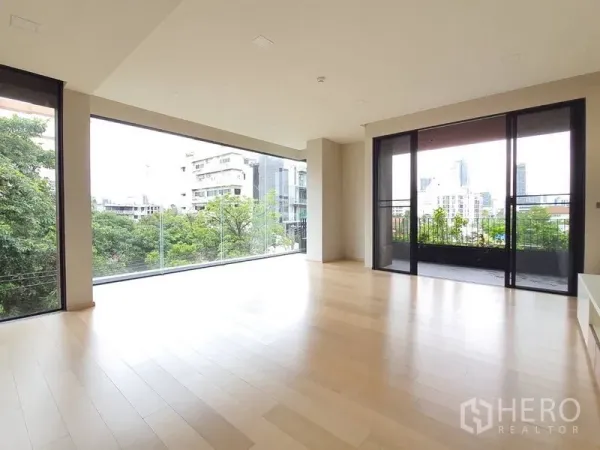 Condominium for sale in Huai Khwang, Bangkok - Bright corner living area with panoramic windows and sliding doors to a balcony facing the skyline.