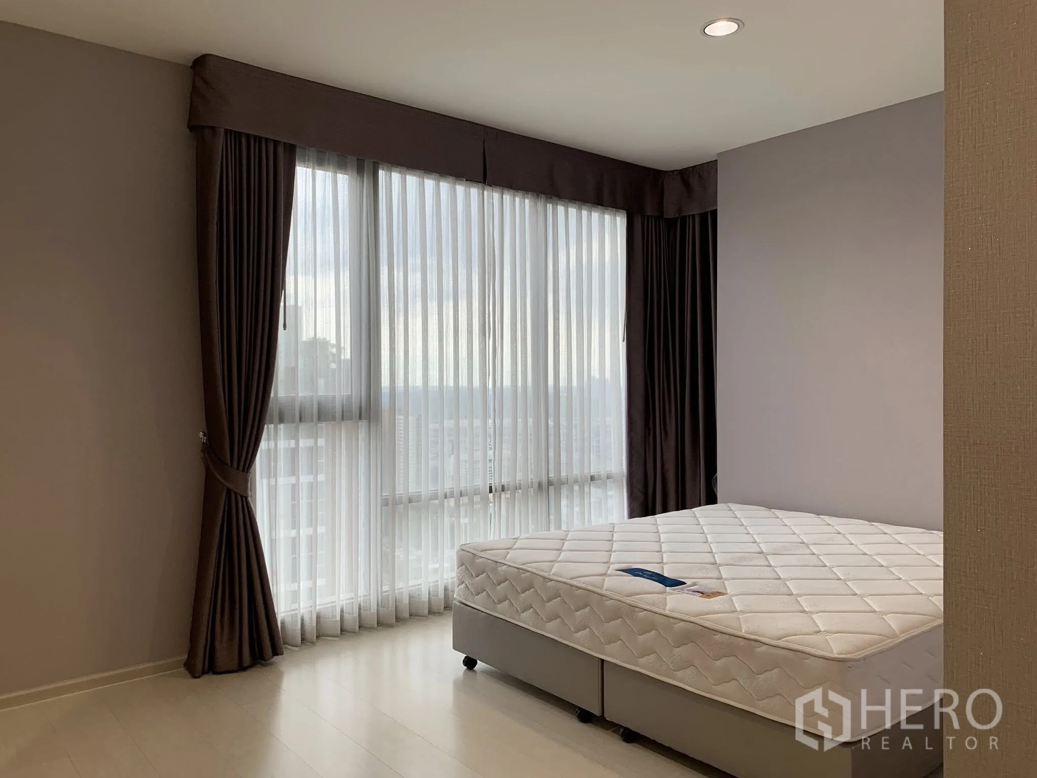 Condominium for rent in Khlong Toei, Bangkok - Corner bedroom with large windows, sheer and blackout curtains, and a queen-size bed.