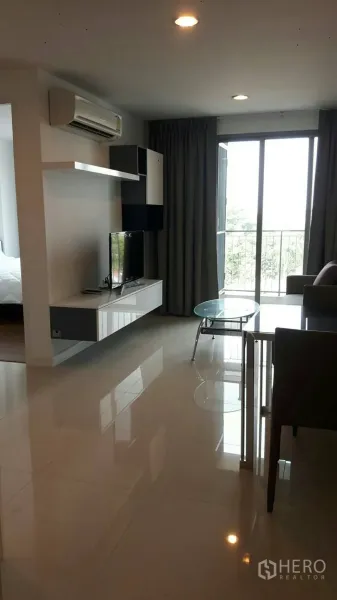 公寓 出租在Phaya Thai, Bangkok - 帕亚泰公寓明亮客厅，墙面电视柜、空调与推拉门连接阳台。