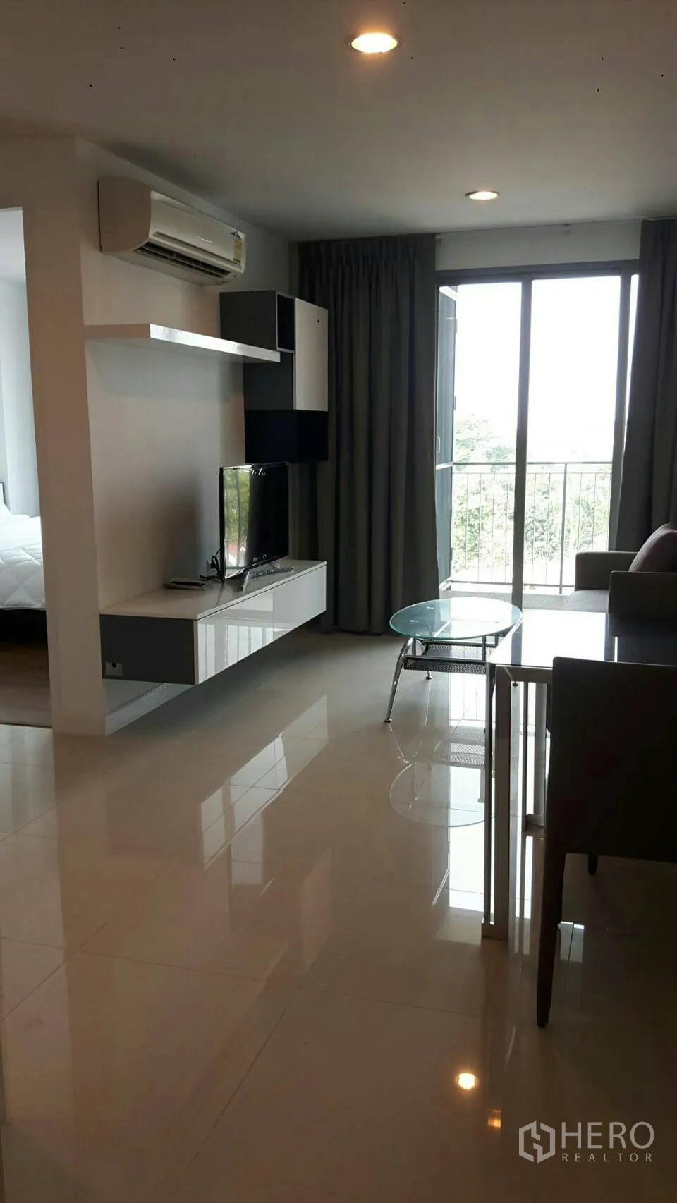 公寓 出租在Phaya Thai, Bangkok - 帕亚泰公寓明亮客厅，墙面电视柜、空调与推拉门连接阳台。