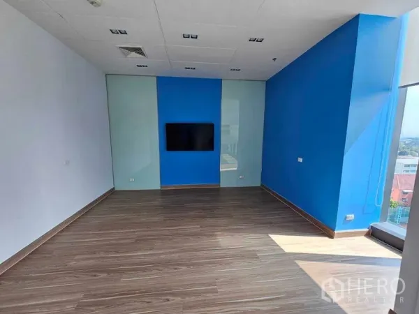 Office Space for rent in Sathon, Bangkok - Meeting room with wall-mounted screen, blue feature wall and corner window view.