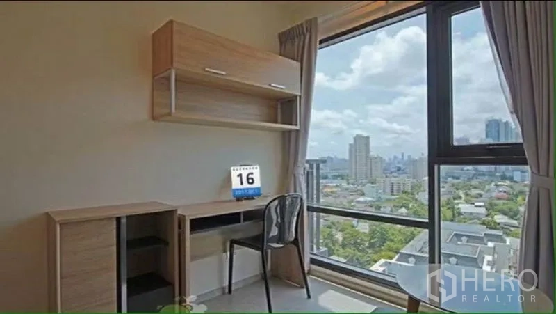 Condominium for rent in Khlong Toei, Bangkok - Work desk beside a large window with built-in shelving and expansive city views.