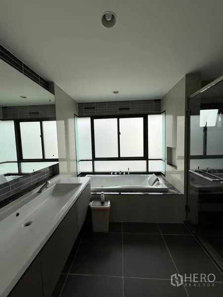 Detached House for rent in Bang Kapi, Bangkok - Master bathroom with bathtub by frosted windows and long vanity.