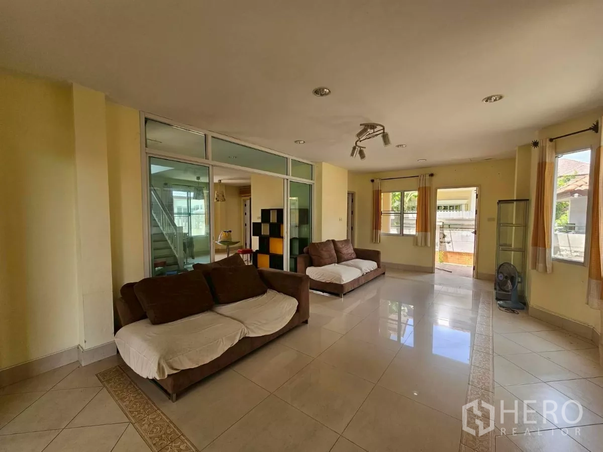 Detached House for rent or sale in Bang Lamung, Chon Buri - Living room from another angle with multiple seating areas and windows.