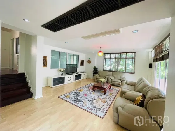 บ้าน ให้เช่าในWatthana, Bangkok - พื้นที่นั่งเล่นกว้าง พร้อมชั้นวางทีวี บันได และหน้าต่างมุมมองต้นไม้