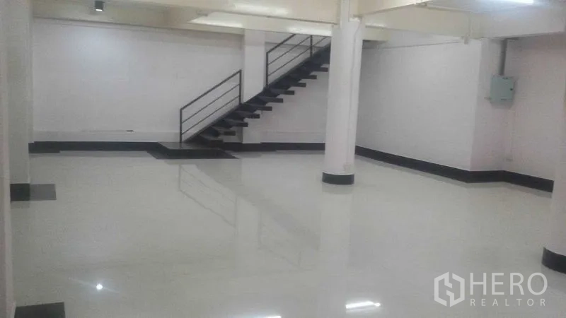 Shophouse for rent in Sathon, Bangkok - Spacious open-plan shophouse interior with glossy tile floors, structural columns and a steel staircase.