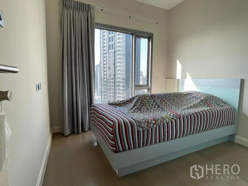 คอนโด ขายในKhlong Toei, Bangkok - ห้องนอนพร้อมหน้าต่างวิวเมือง เตียงลายทาง ผ้าม่านสีเทา