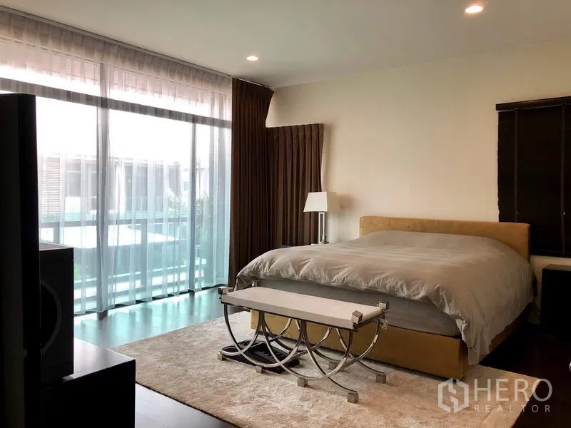 Detached House for rent or sale in Bang Kapi, Bangkok - Spacious master bedroom with large glass wall, balcony access and soft lighting.
