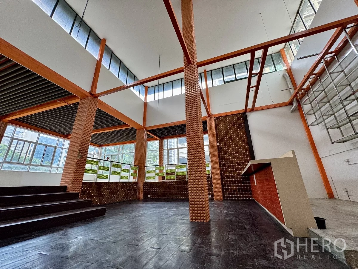 Shophouse for rent in Sathon, Bangkok - High-ceiling retail space with textured columns, large windows and a counter bar.