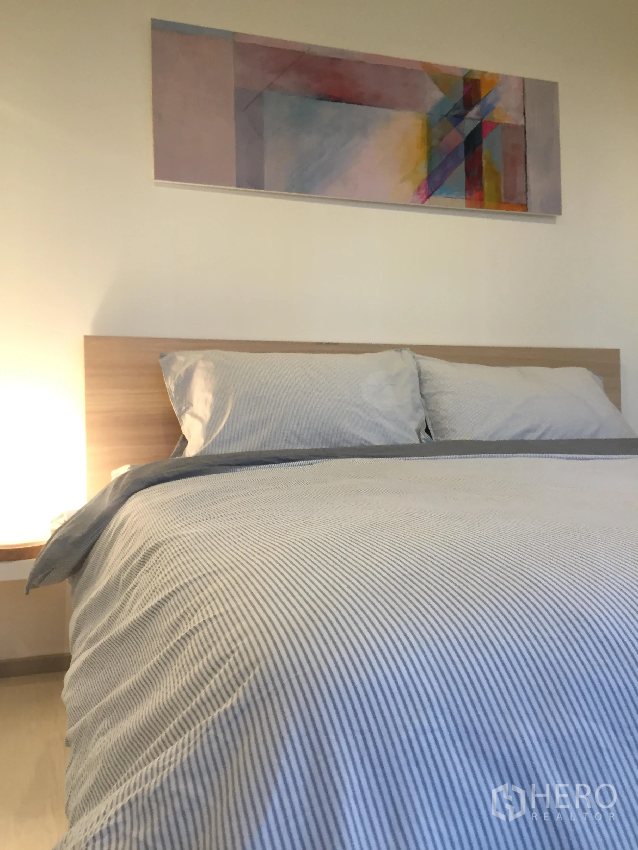 公寓 出租在Khlong Toei, Bangkok - 明亮卧室，双人床、木质床头板，床头上方挂有抽象画。