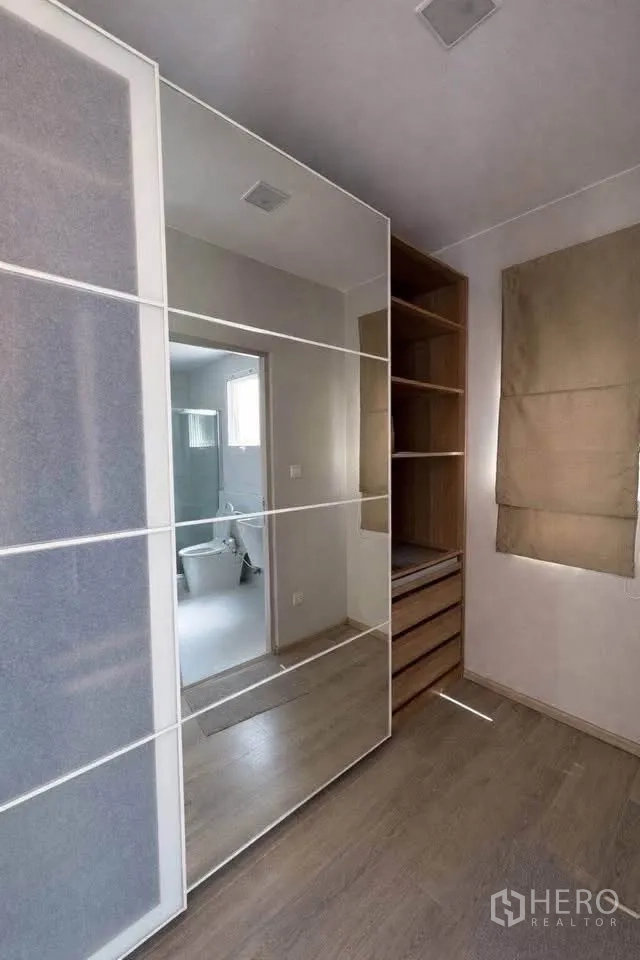 Semi-detached House for rent in Prawet, Bangkok - Dressing area with mirrored wardrobe and shelving next to a bathroom.