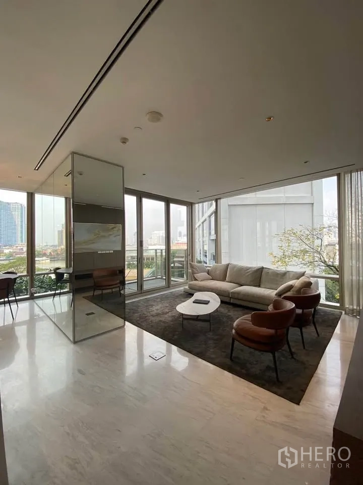 Condominium for rent in Sathon, Bangkok - Spacious open-plan lounge with seating on a dark rug and wraparound windows.