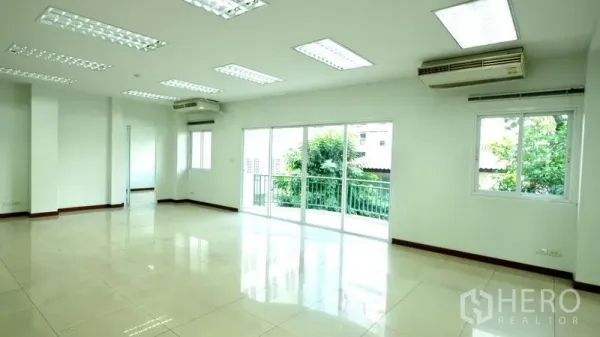 Office Space for rent in Bang Rak, Bangkok - Bright open-plan office with tiled floors, ceiling lights and sliding glass doors to a balcony.