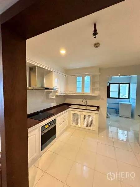 คอนโด ให้เช่าในBangkok - ครัวรูปตัว U ตู้สีขาว เตาอบ เตาไฟฟ้า และอ่างล้างจาน