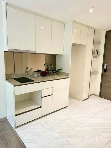 Condominium for rent - Minimal white kitchenette with stone countertop, electric cooktop and ample cabinets.