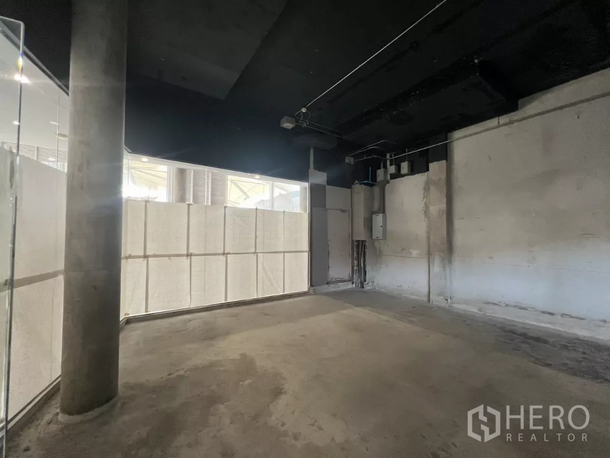 零售空间 出租 - 毛坯室内空间，混凝土地面、黑色外露天花与管线接口。