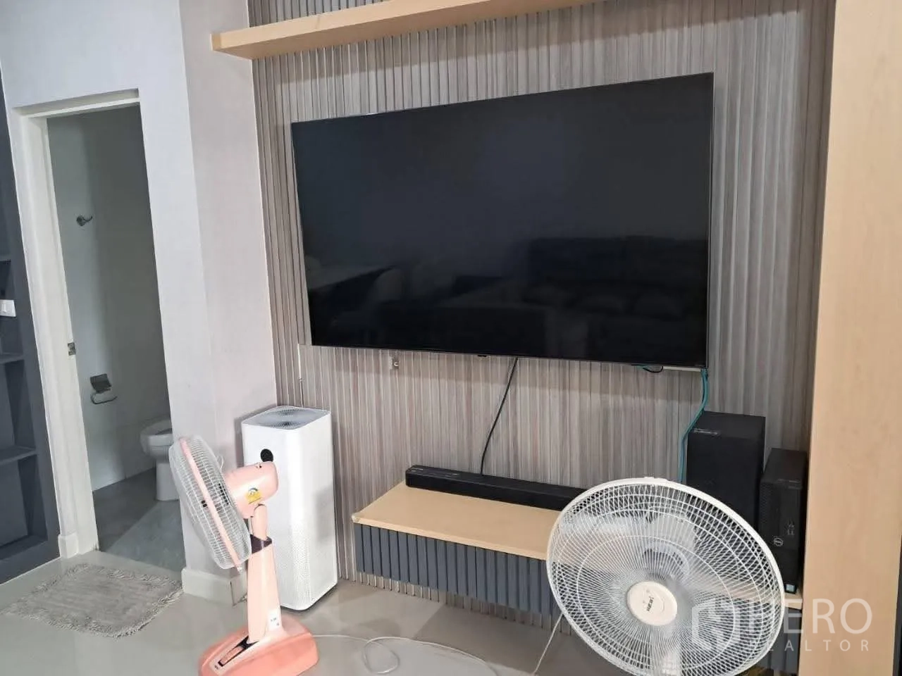 联排别墅 for rent in Bang Kapi, Bangkok - 客厅电视墙安装平板电视，旁边为卫生间门。