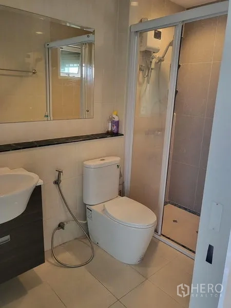Townhouse for rent in Wang Thonglang, Bangkok - Modern bathroom with glass shower enclosure, toilet and basin.