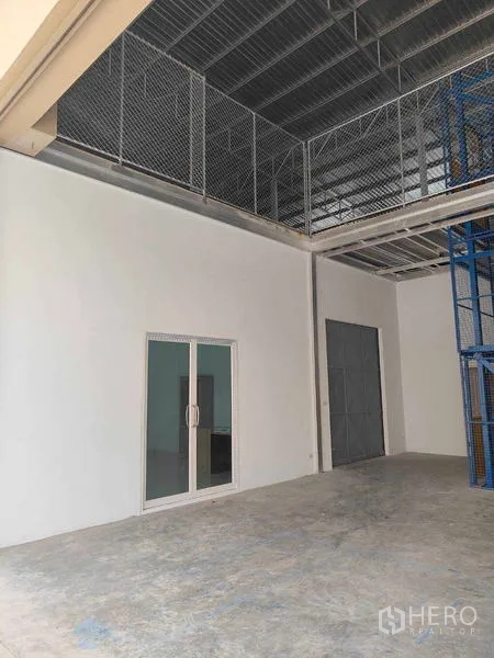 Warehouse for rent in Krathum Baen, Samut Sakhon - Warehouse interior with sliding glass office door and mesh mezzanine level.