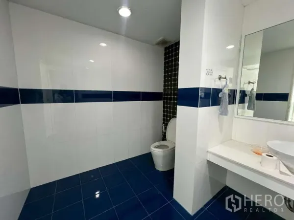 展厅 出租 - 洁净卫生间，白色墙砖搭配蓝色装饰带与大镜面。