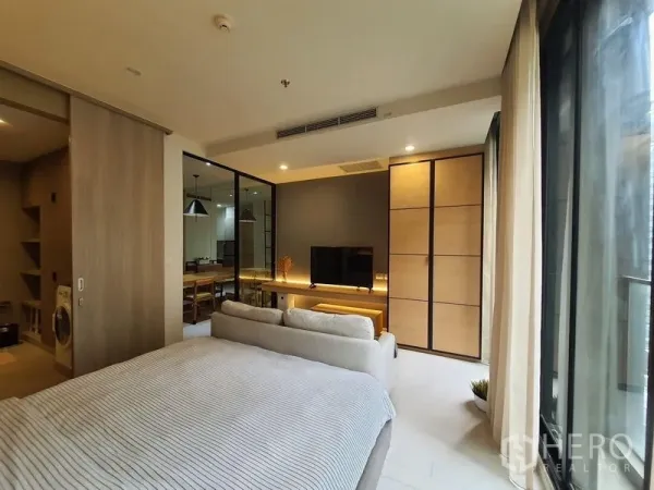 คอนโด ให้เช่าในPathum Wan, Bangkok - ห้องนอนมีผนังทีวี ตู้เสื้อผ้าใบใหญ่ และประตูกระสไลด์สู่โซนรับประทานอาหาร แสงธรรมชาติเต็มห้อง