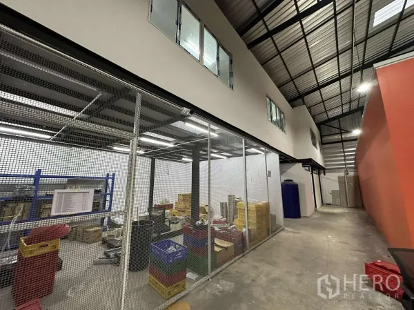 货栈 出租 - 一层网笼式储物与工作区，旁为带窗的两层办公区。