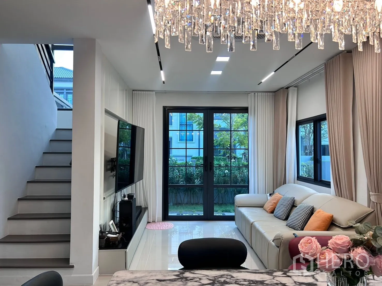 Semi-detached House for rent in Bang Phli, Samut Prakan - Living area with sofa and TV wall opening to the garden via sliding doors.